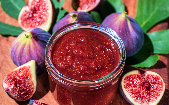 Jar of fig jam beside ripe figs