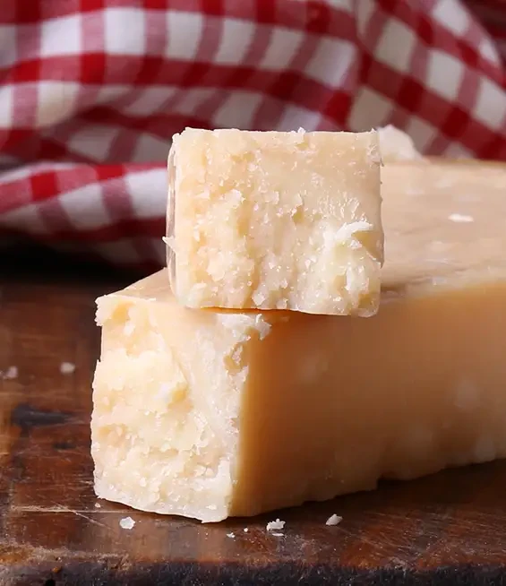 Pieces of pale crumbly cheese on a wooden board