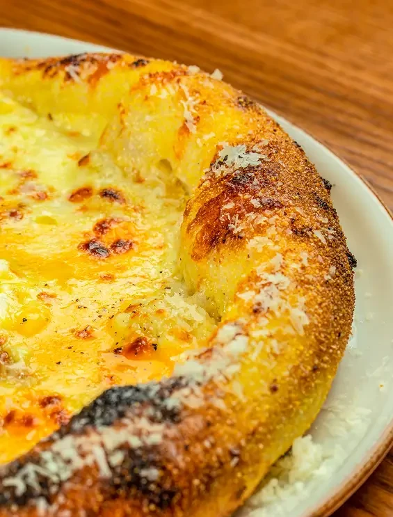 Close view of a baked pizza topped with golden melted cheese