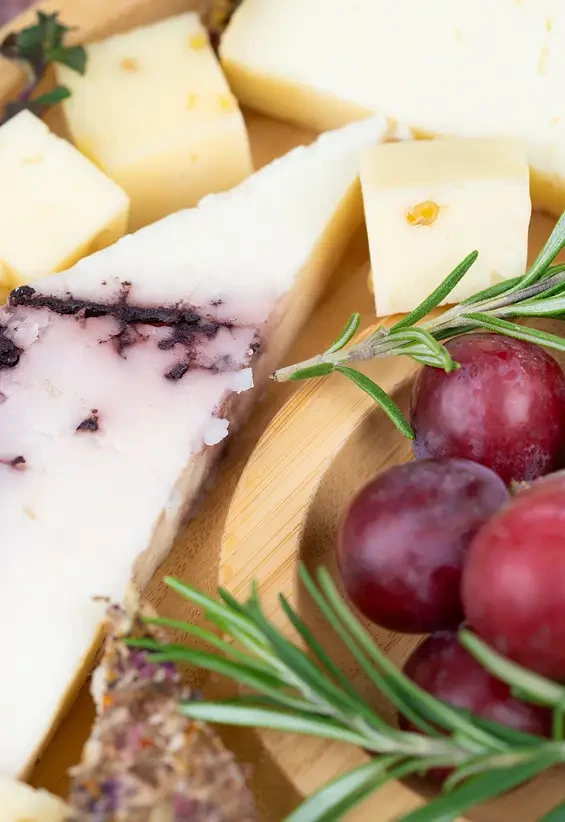 Close view of cheese wedges beside grapes and rosemary