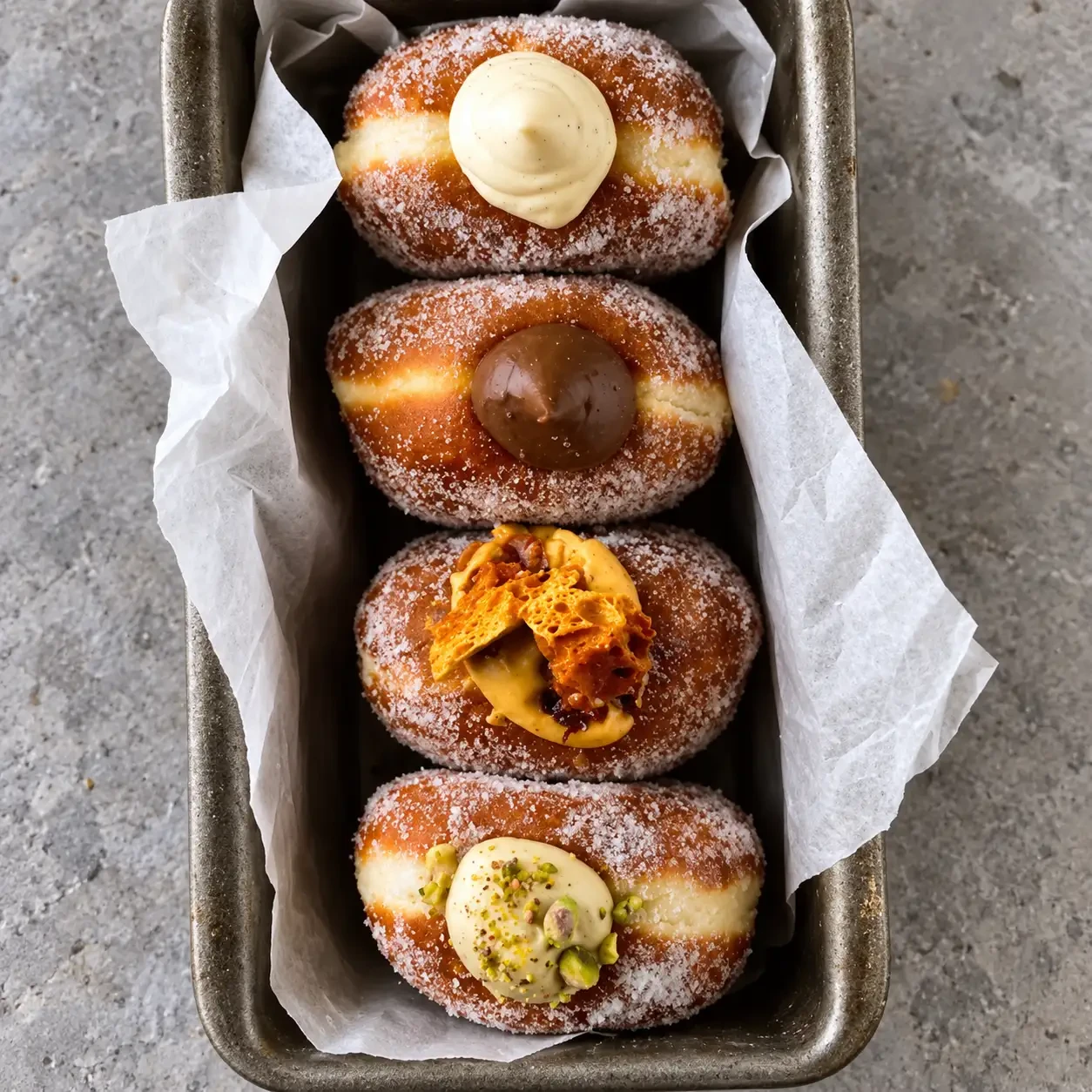 Four filled doughnuts with different toppings on a tray