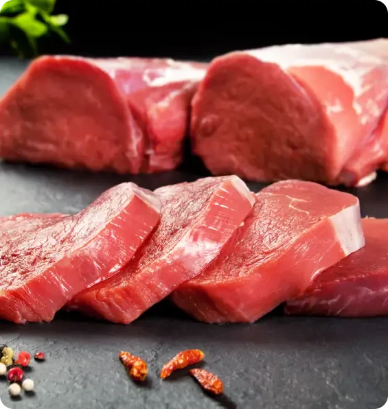Thick slices of raw red meat on a dark surface