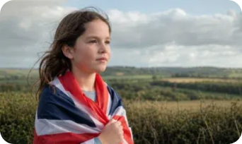 Woman wrapped in a Union Jack flag overlooking countryside