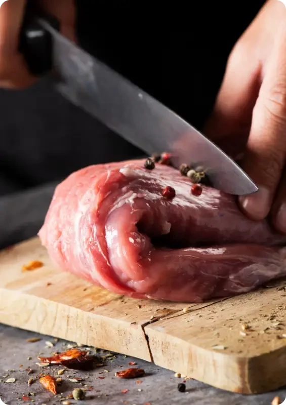 A butcher slicing a rolled cut of raw meat