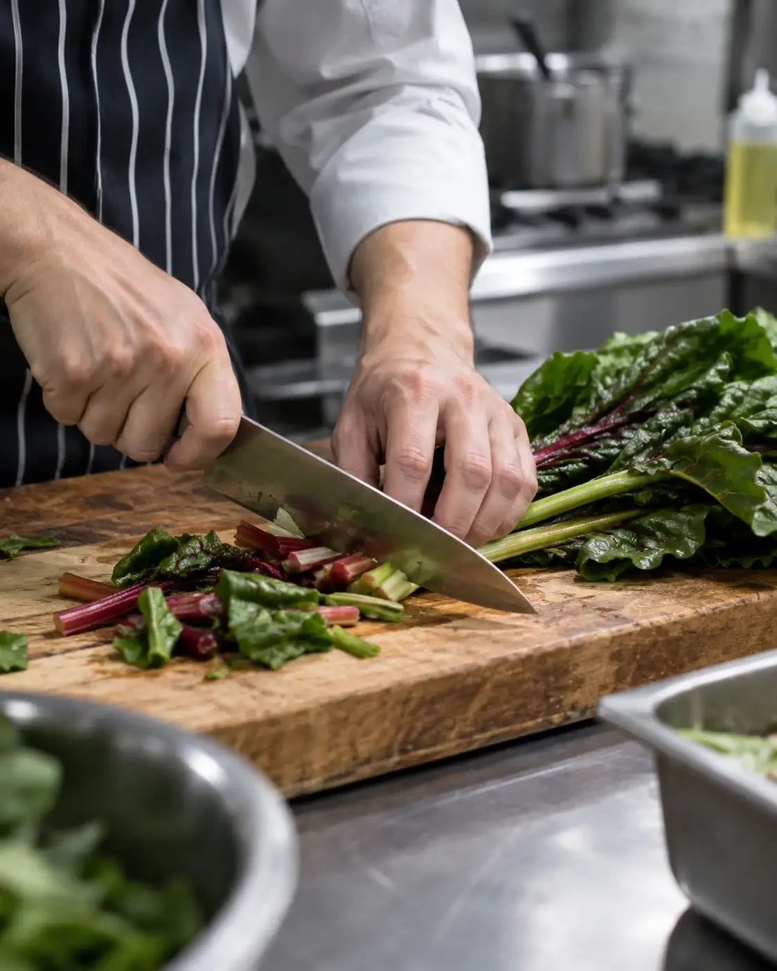 Chef chopping leafy greens on a wooden board