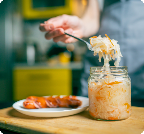 Spoon lifting fermented vegetables from a jar
