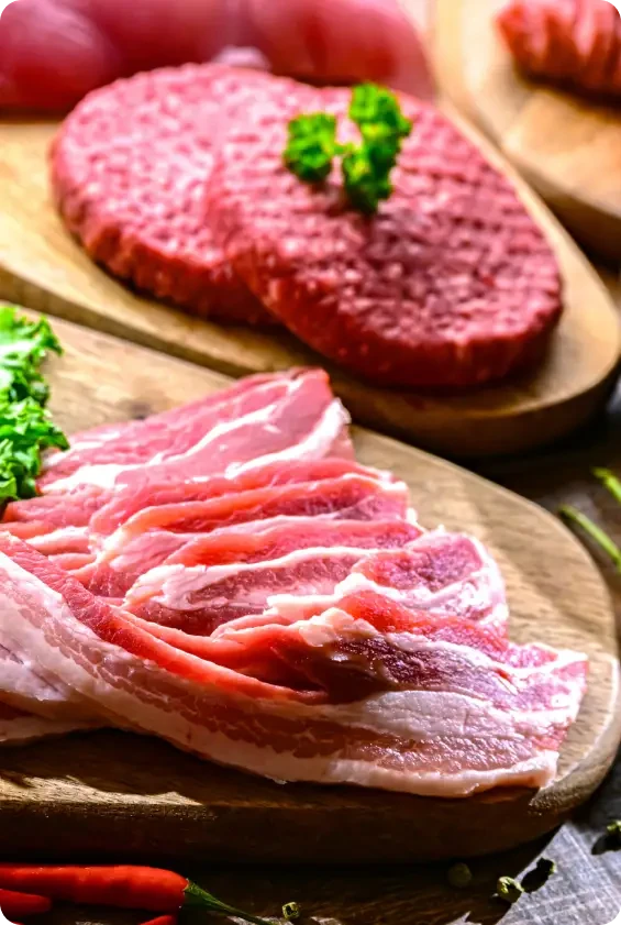 Raw burger patties and sliced meat on wooden boards