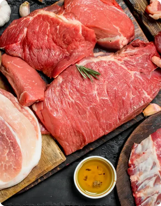 Different cuts of raw meat arranged on a dark board