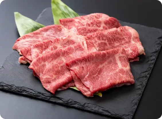 Thin slices of marbled raw meat arranged on a dark plate