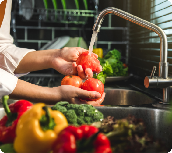 Person washing tomatoes under a kitchen tap