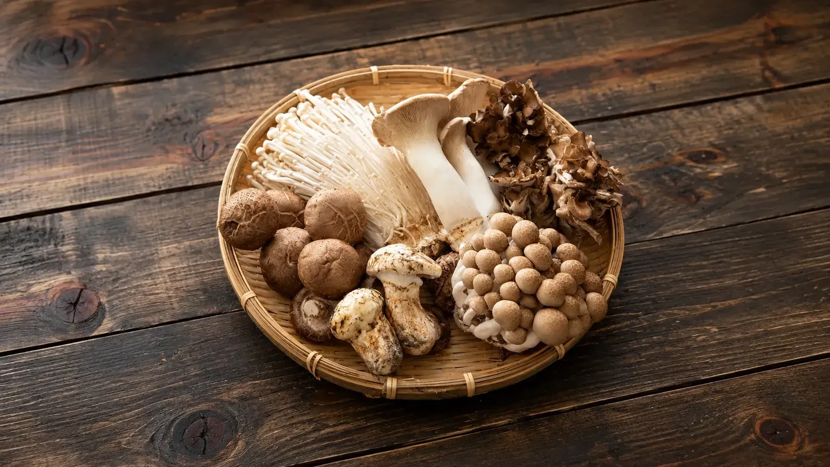 A mixed selection of mushrooms in a shallow woven basket