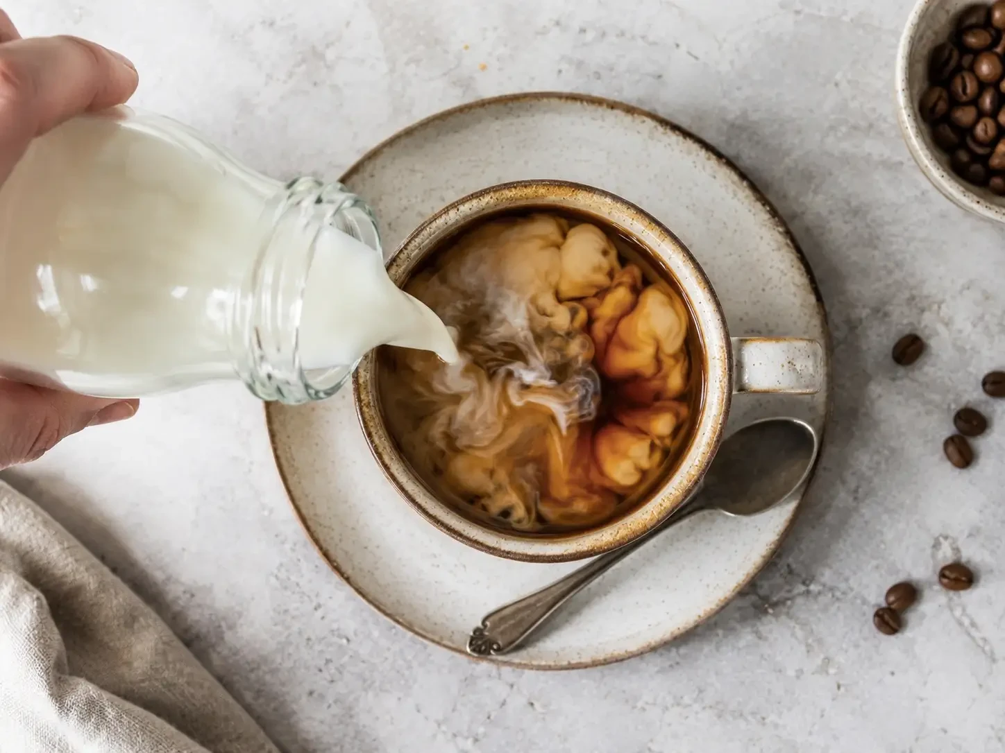 Milk being poured into a cup of coffee