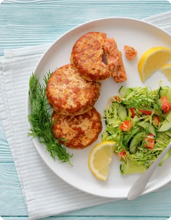 Three golden fishcakes served with salad and lemon