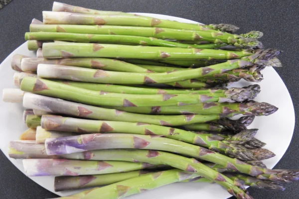 Green asparagus spears arranged on a white plate