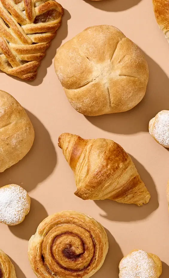 Bread rolls and pastries arranged on a pale surface