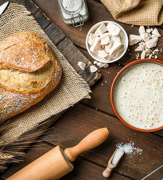 Bread, yeast and baking ingredients beside a rolling pin
