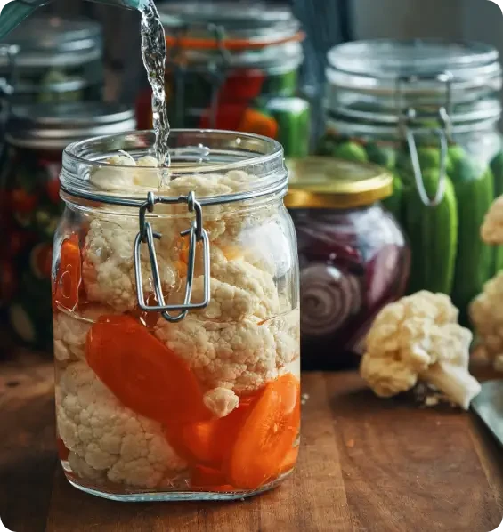 Liquid being poured into a jar of cauliflower and carrots