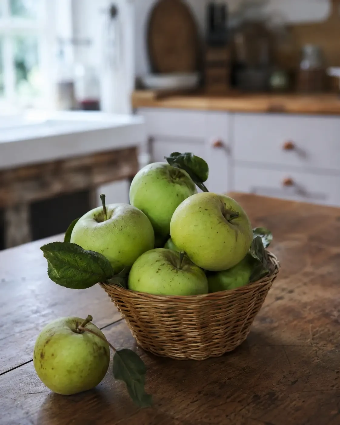 A basket of green cooking apples on a kitchen counter