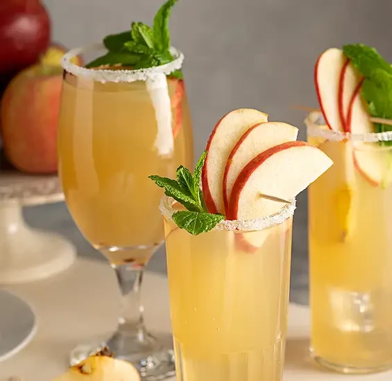 Golden drinks garnished with apple slices and mint