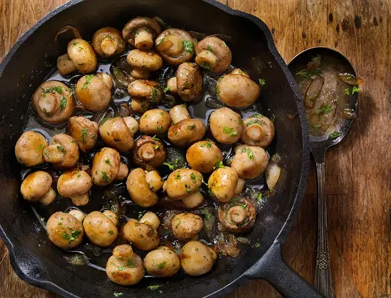 Whole mushrooms cooked with herbs in a frying pan