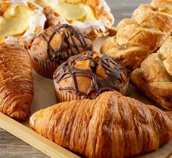 Croissants and muffins arranged together in a basket