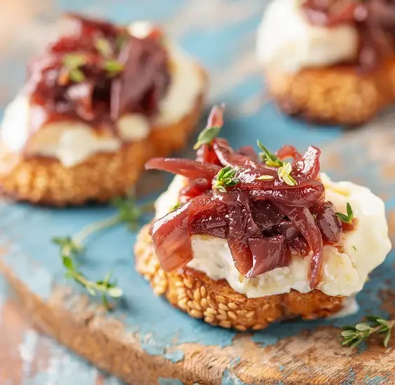 Small toasts topped with soft cheese and red onion chutney