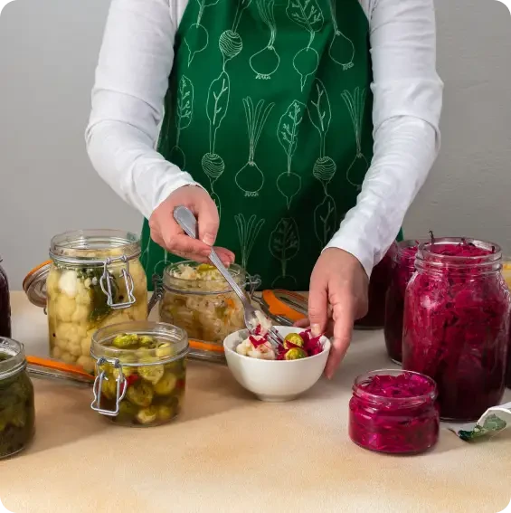 A person serving mixed vegetables from jars into a bowl