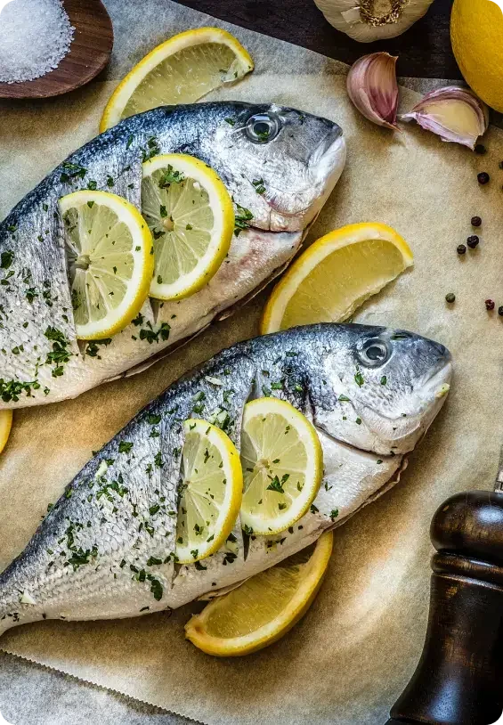 Two whole fish prepared with lemon slices and herbs