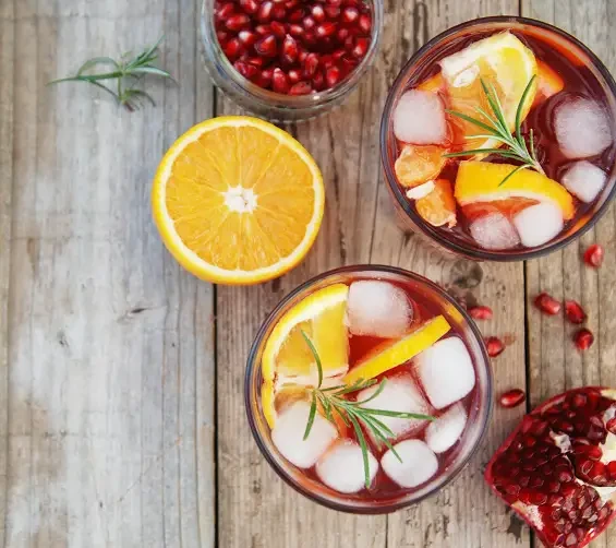 Fruit drinks with ice, citrus slices and pomegranate seeds