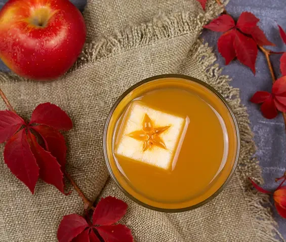 An amber drink garnished with apple and star anise