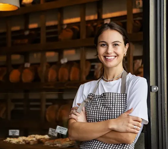 A smiling baker standing in the doorway of a bakery