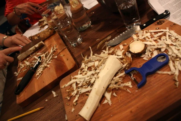 Horseradish root being peeled on a wooden preparation board