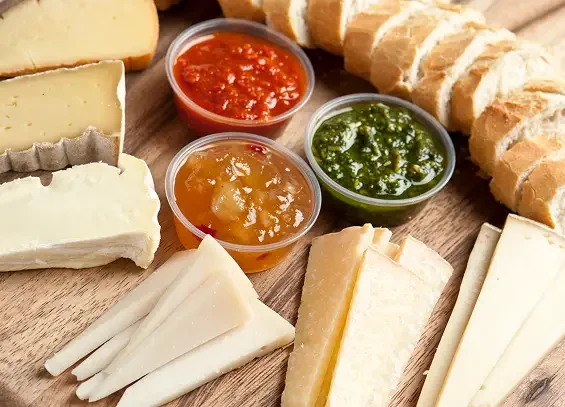 A cheese board with bread and three colourful chutneys