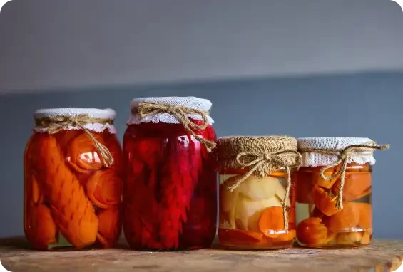 Four jars of colourful preserved vegetables with fabric covers
