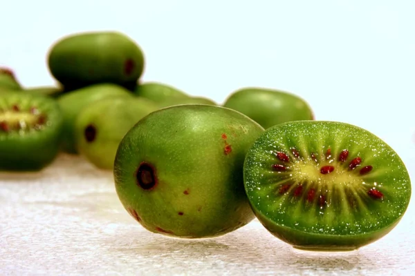 Whole and cut smooth skinned hardy kiwi fruits