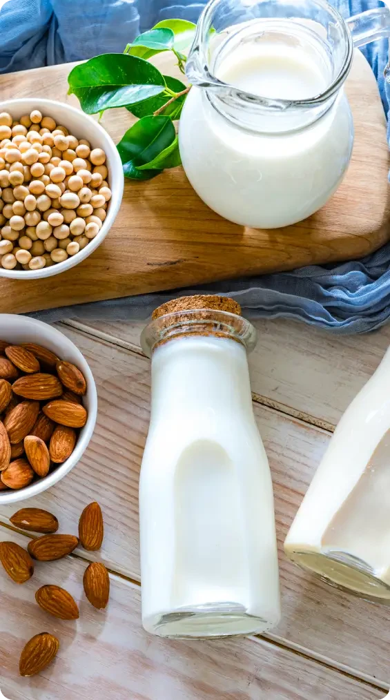 Bottles of white drink beside almonds and dried beans