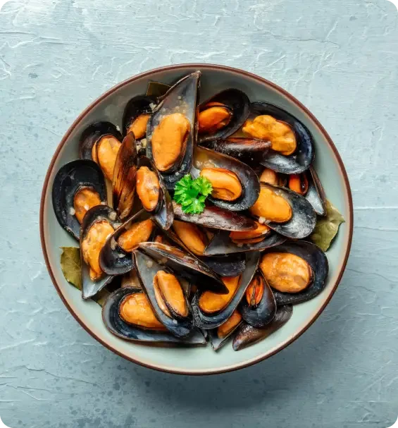 A bowl of cooked mussels with a parsley garnish