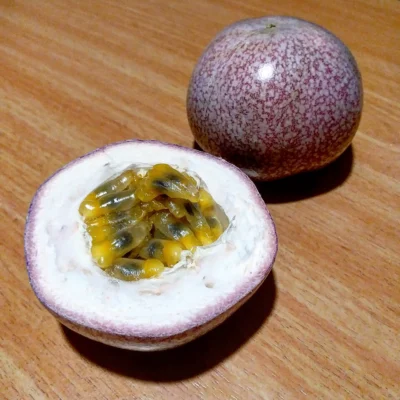 Whole and halved purple passionfruit with yellow pulp and dark seeds