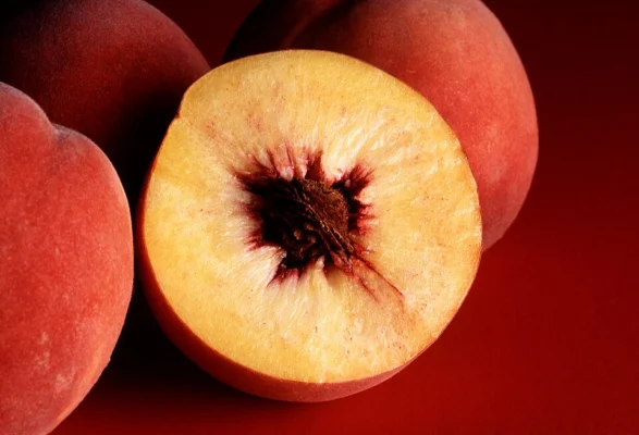 Whole and cut Autumn Red peaches showing yellow flesh