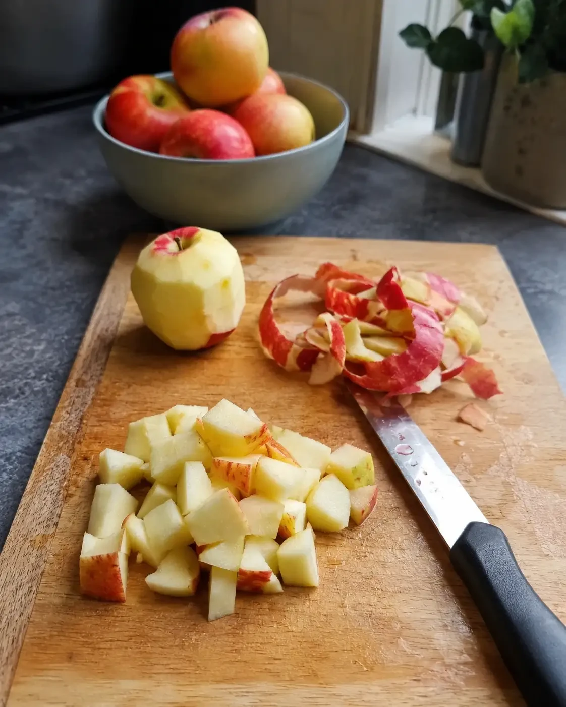 Chopped and peeled apple on a board beside a knife and apple peel