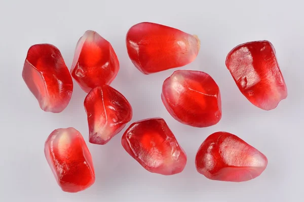 A close view of separate juicy red pomegranate arils on a white background