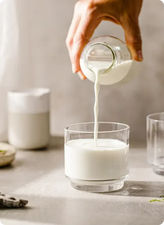 Milk being poured from a small bottle into a glass