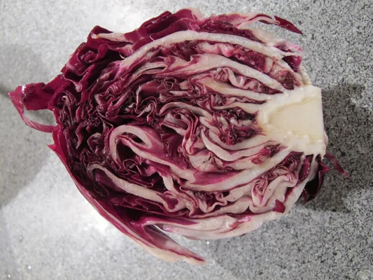 A red radicchio head cut in half to show its layered leaves