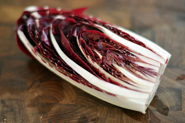 A halved elongated radicchio showing white ribs and red leaves