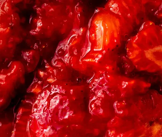 Close view of strawberry pieces in glossy red jam