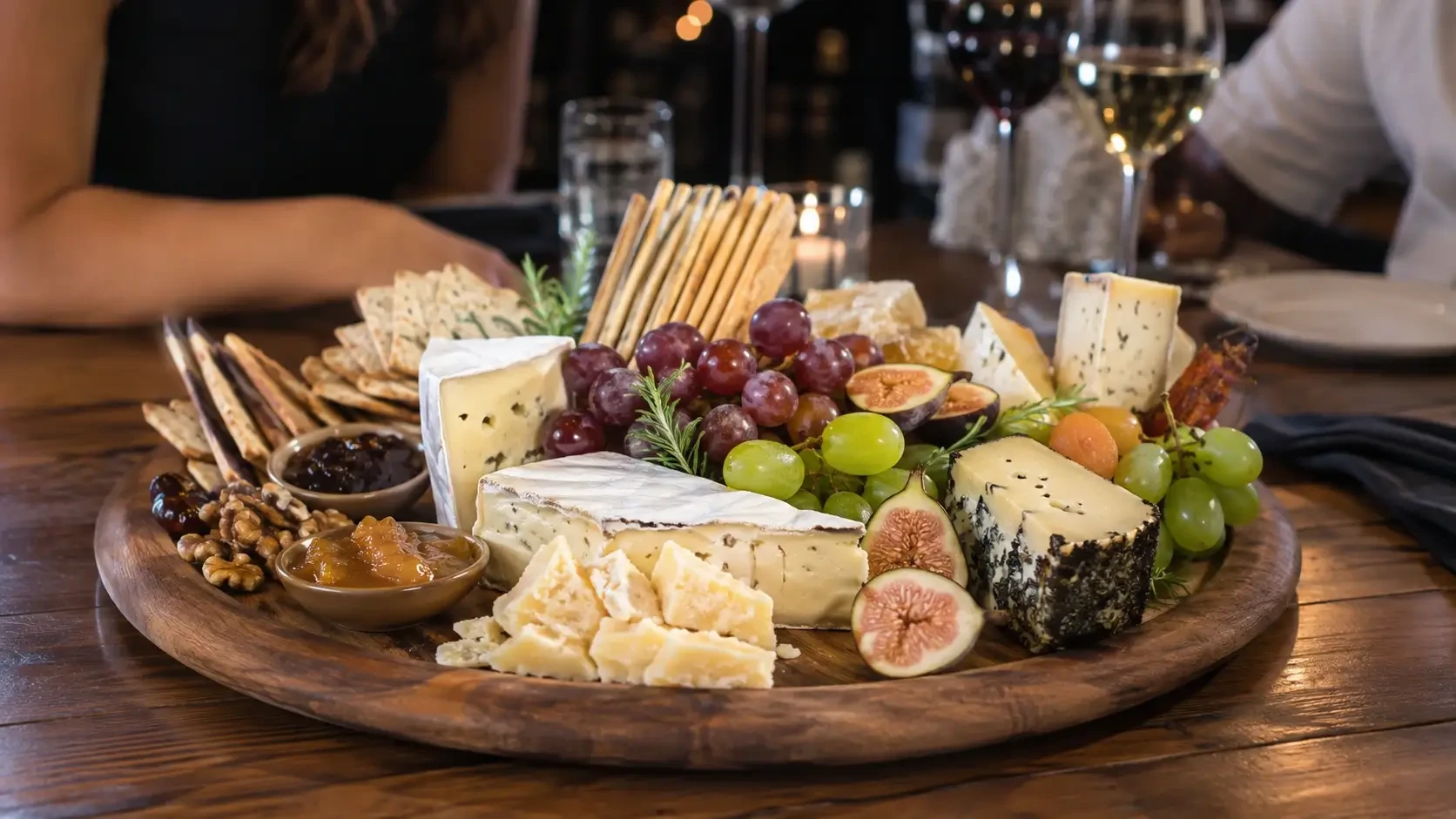 A large cheese board with grapes, figs, crackers and nuts