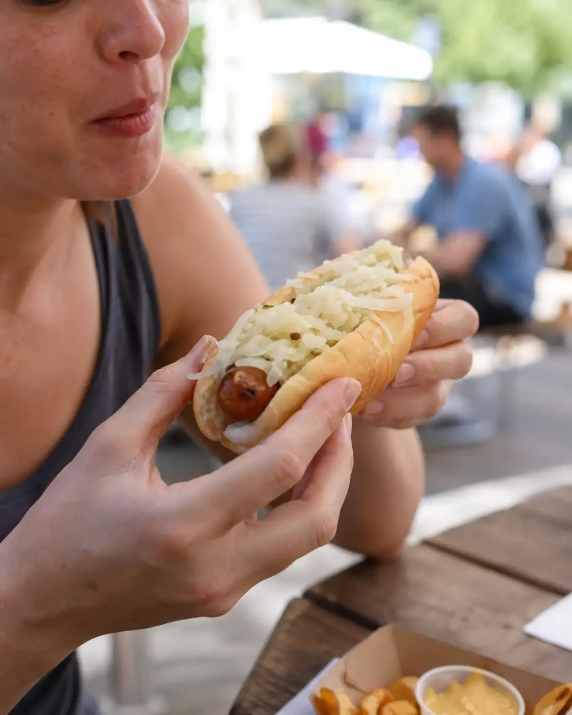 A person holding a hot dog topped with shredded cabbage