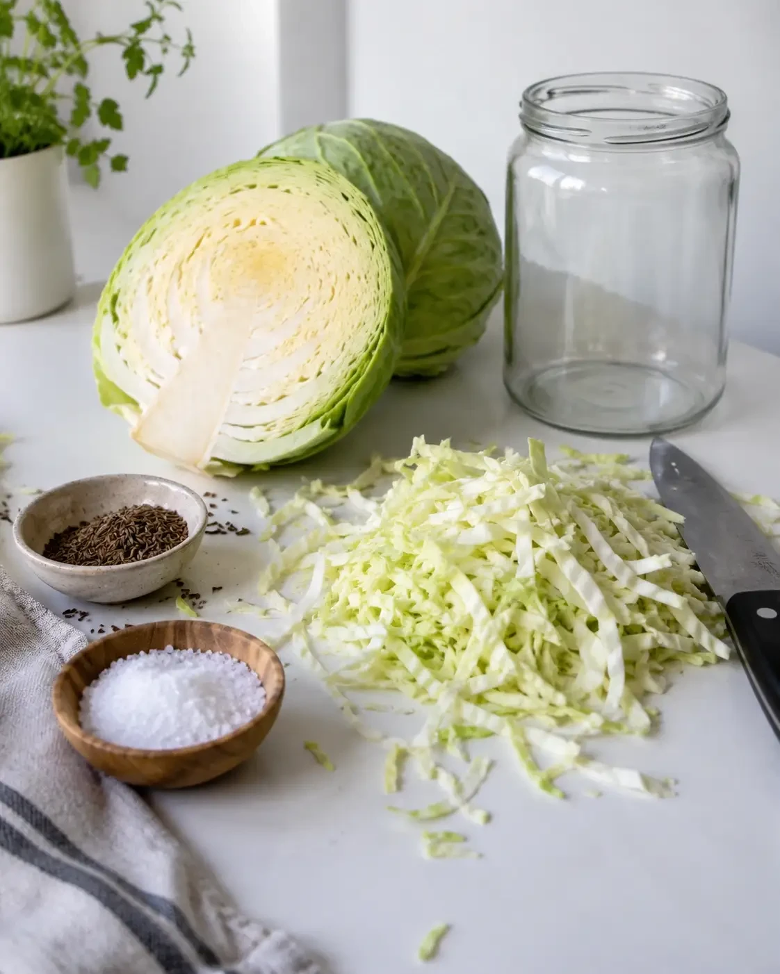 Shredded cabbage beside salt, spices and an empty glass jar