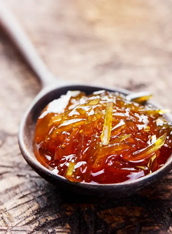 Orange marmalade with strips of peel on a dark spoon