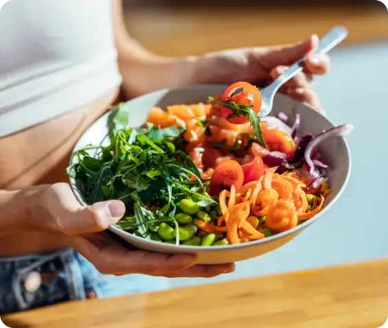 A person holding a bowl of colourful mixed salad